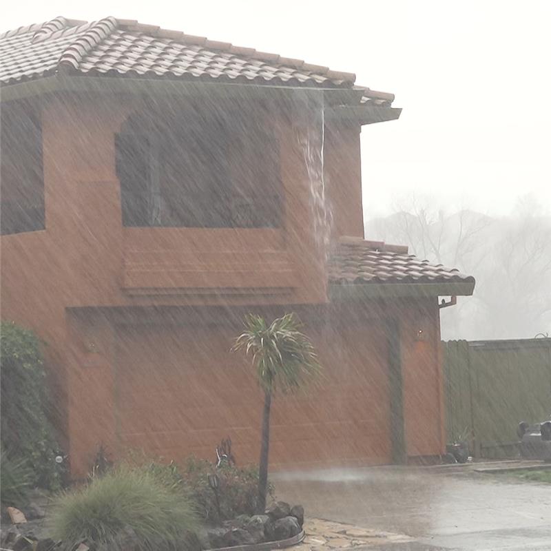 fda134f4-1e93-468b-b25b-dcaa807ca2fc An image of a stucco house and front yard in heavy rain.