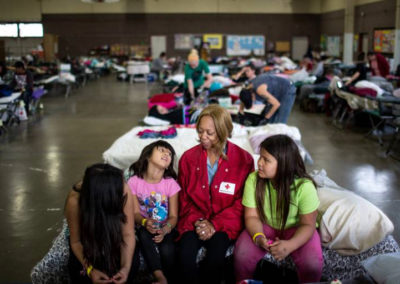 Red Cross Volunteer sits with three evacuees