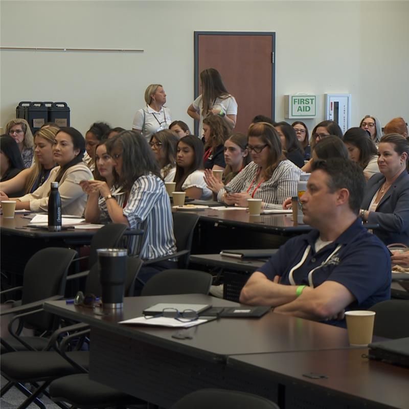 A group of emergency managers are seated at Cal OES headquarters, looking toward the front of the room during a presentation.